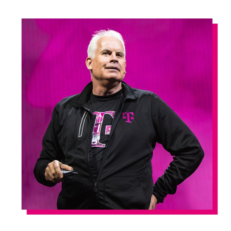 Neville Ray speaking on a stage in front of a magenta background