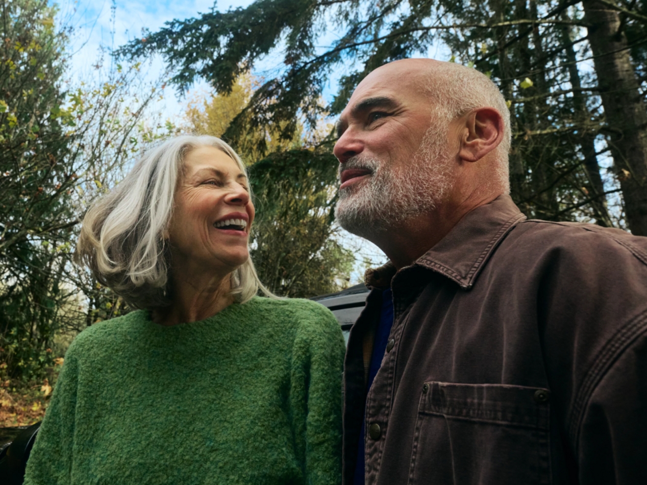 An older couple smiling together outside.