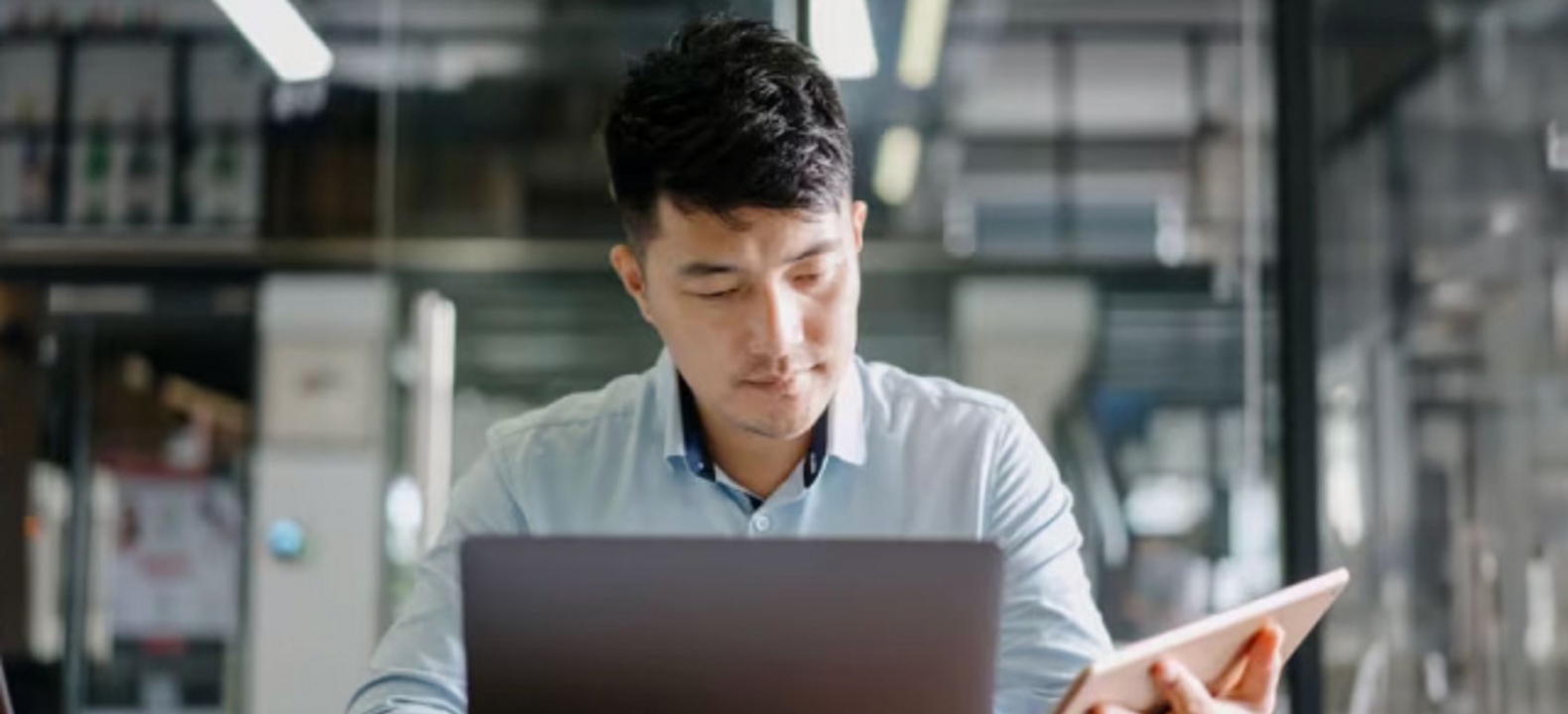 A young professional uses a laptop and tablet simultaneously.