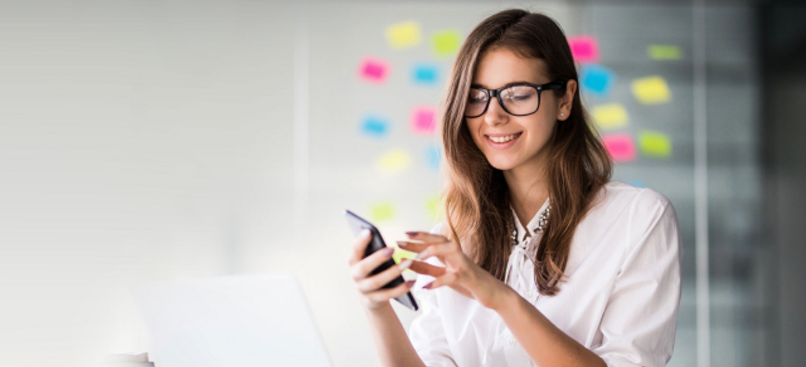 A smiling professional on her smartphone in a modern office environment.