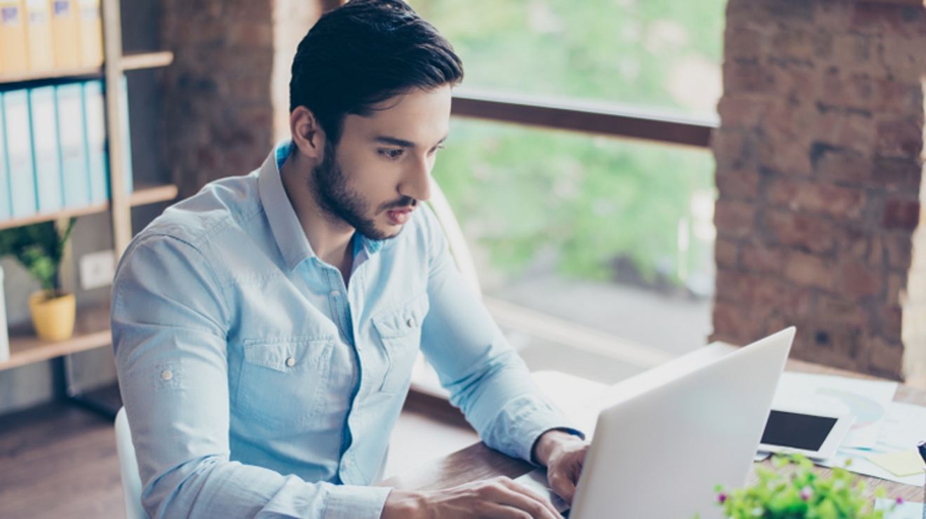 Young man focuses intently as he types on his laptop.