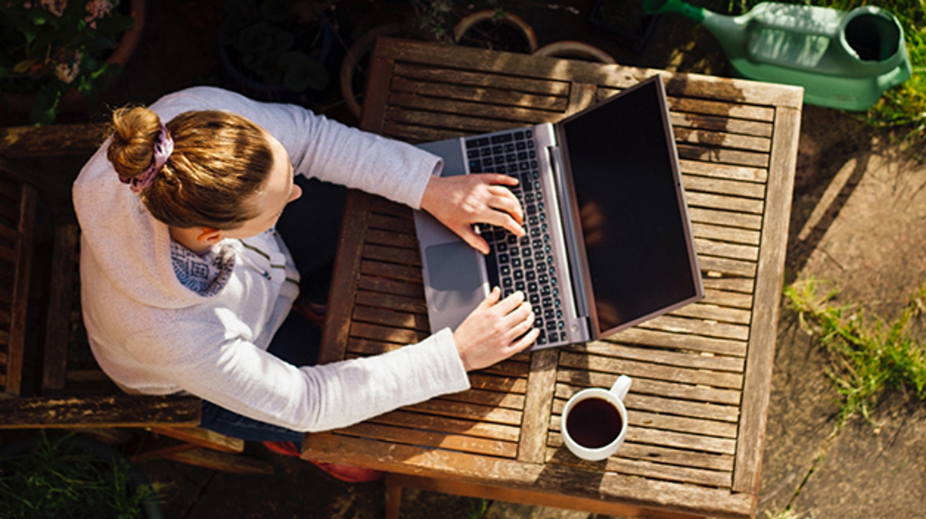 Bird’s eye view of woman working outside on a laptop.