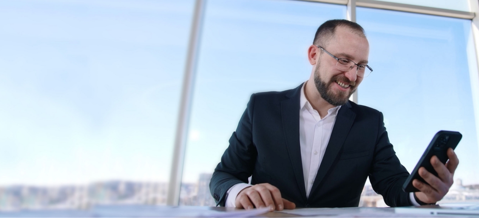 A smiling professional checks his smartphone.
