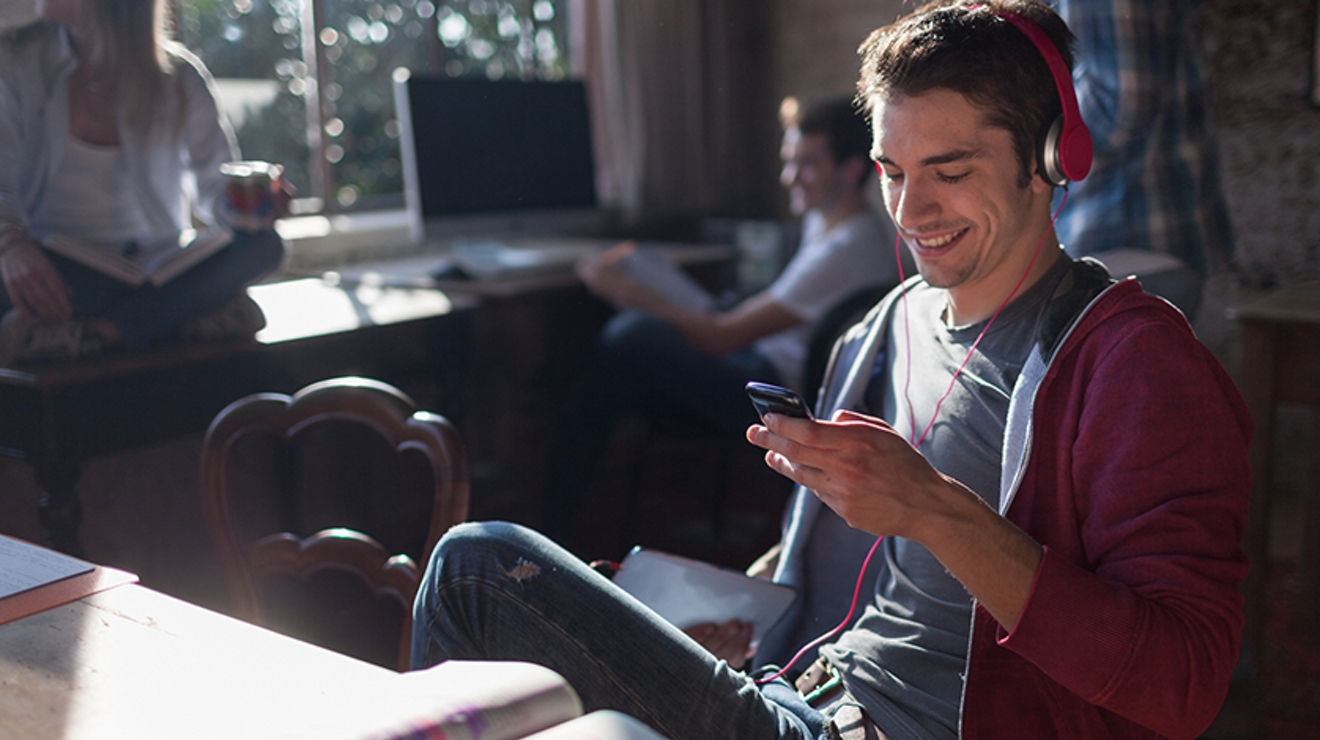 student listening to music with earphones and device