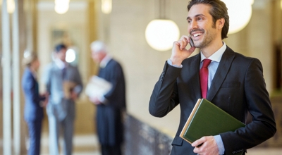 A professional talks on his smartphone in a company hallway.