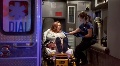 An EMT comforts a patient in an ambulance.