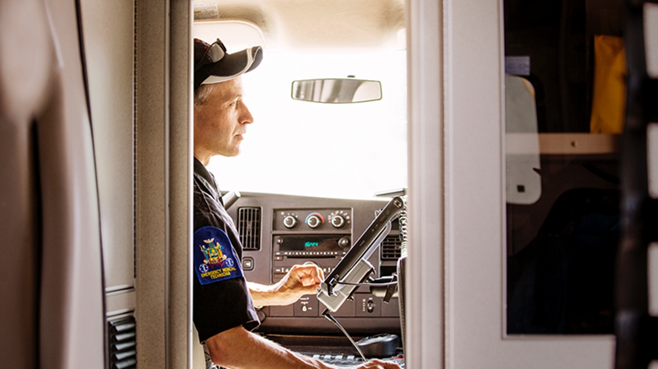 A man in a uniform sits in the front of a truck looking at a mounted monitor screen