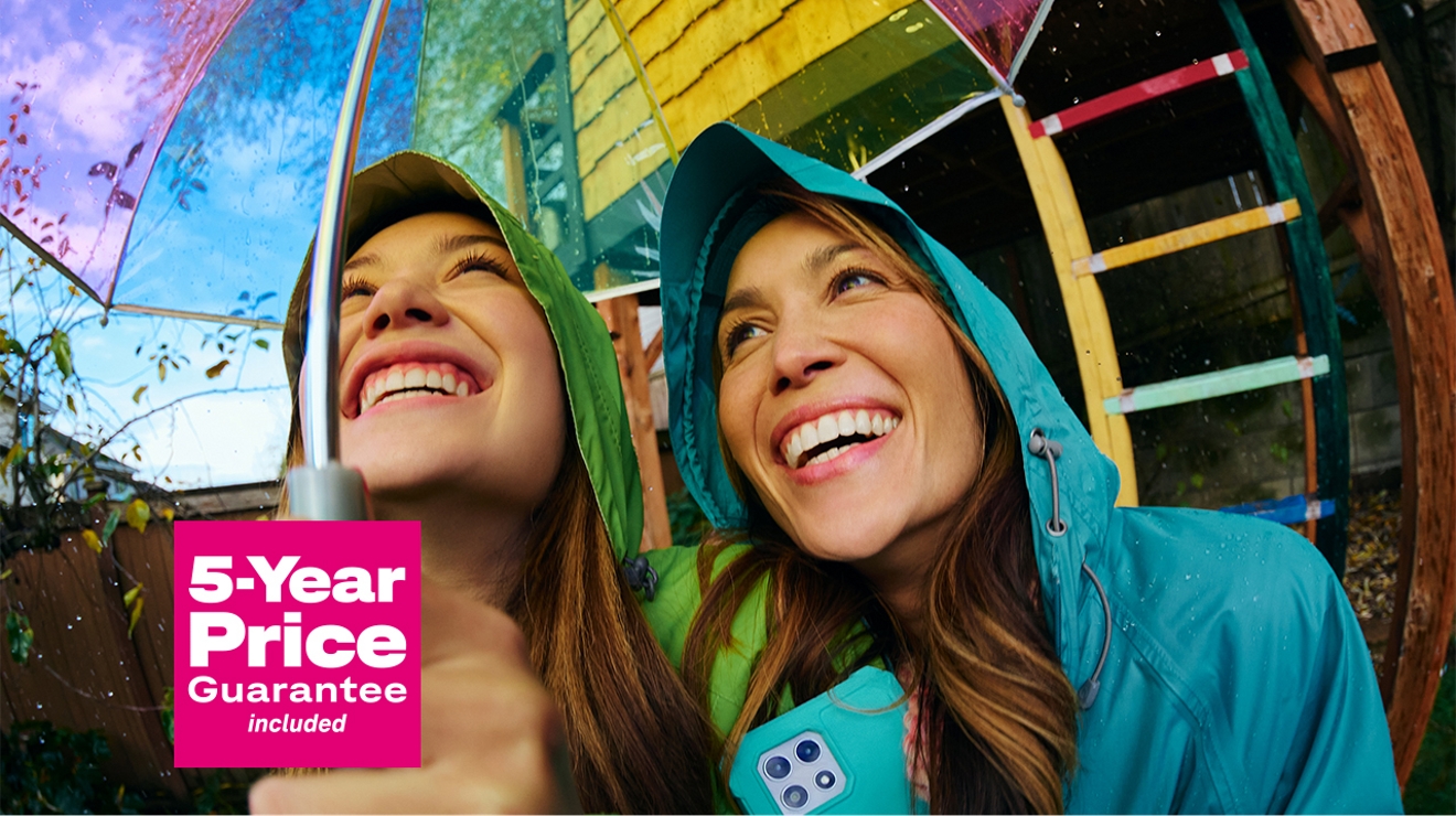 Laughing, two young women huddle under an umbrella, with the words “five-year price guarantee included.