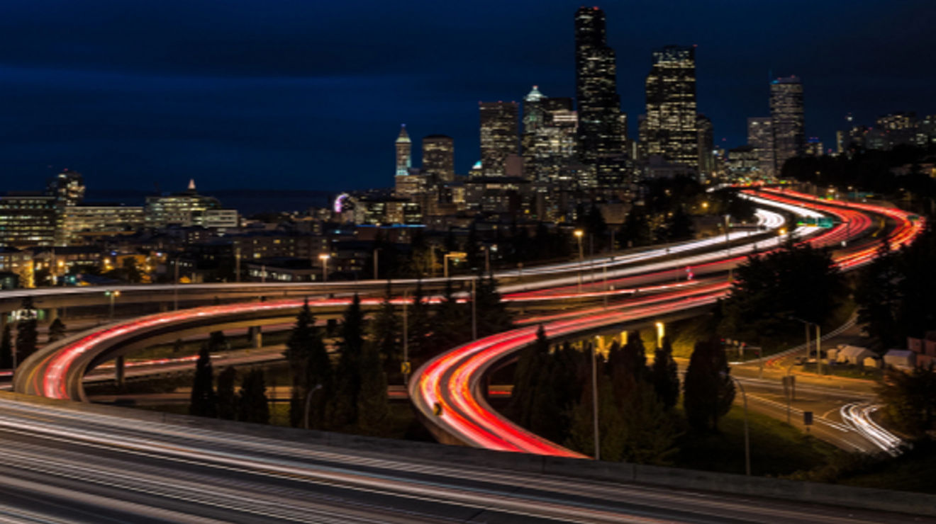 Glowing highways lead into a city at night.