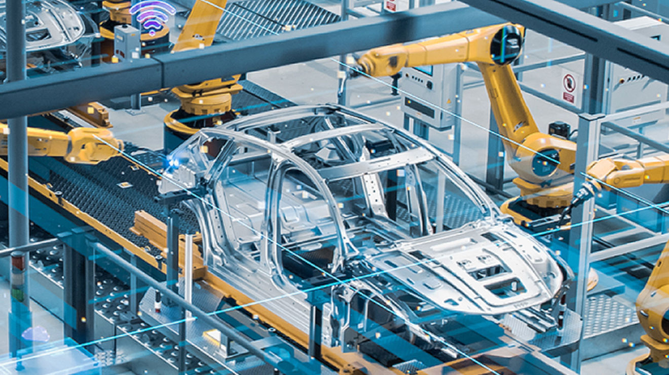 Car frames on assembly line with orange robotic arms.