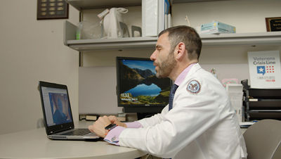 Veterans Affairs office employee sitting at a desk while using laptop.