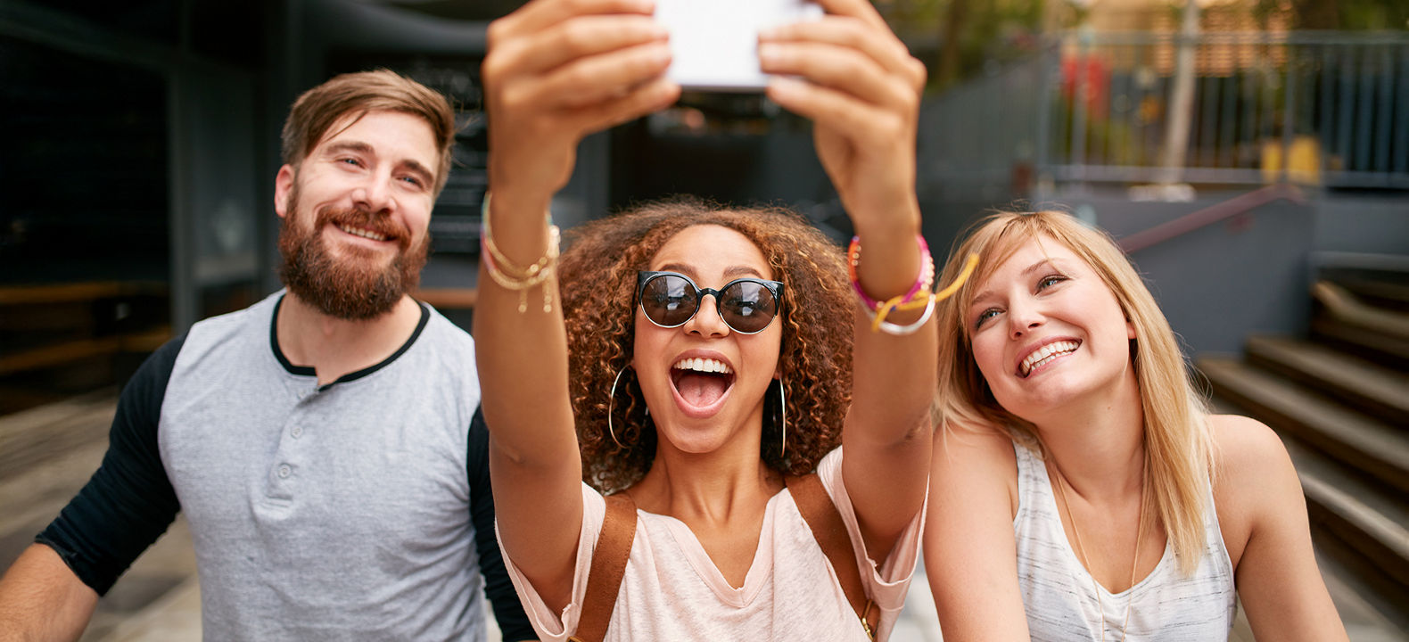 A woman holds her phone up to take a selfie with two friends.