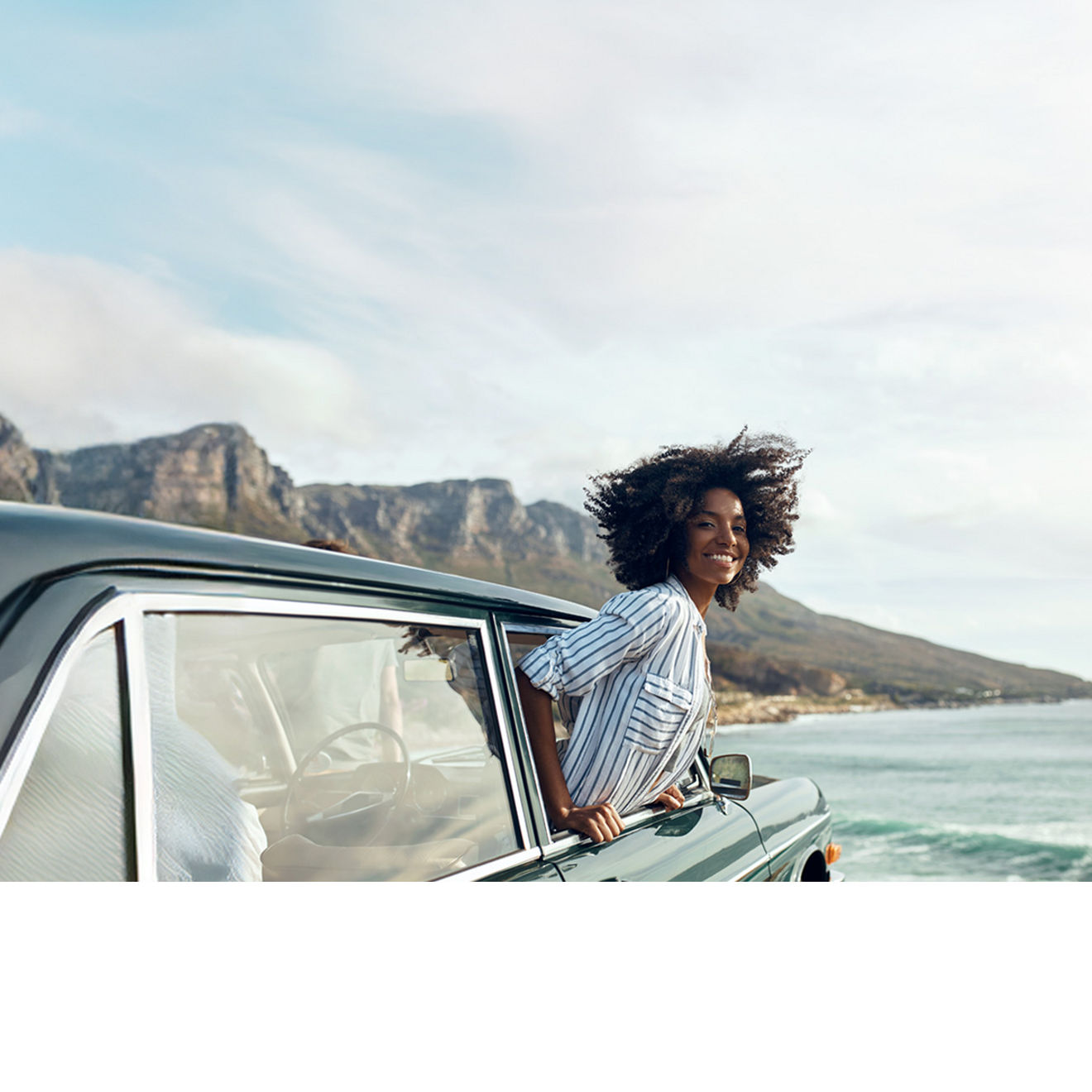 Woman smiling with her head out of a car